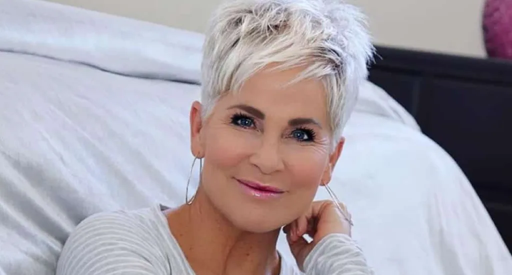 A close-up portrait of a mature woman with a modern, textured white pixie cut featuring soft layers and subtle styling.