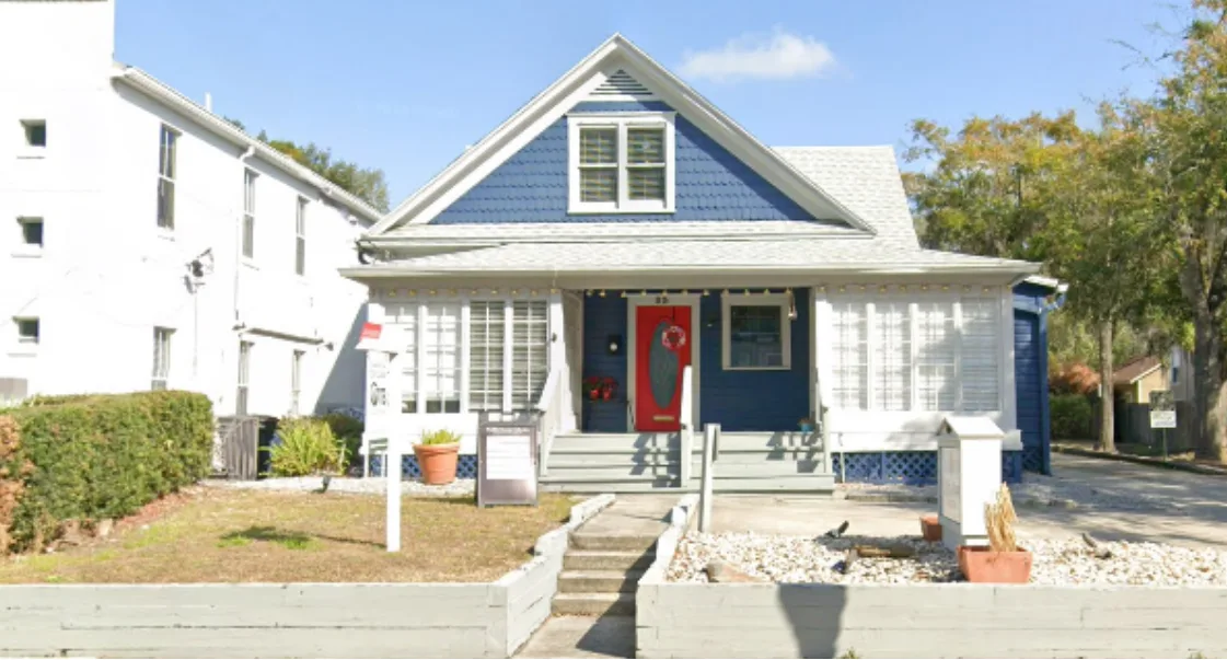 Front exterior of a white and blue residential style house used as the Orlando Men's Hair Studio.